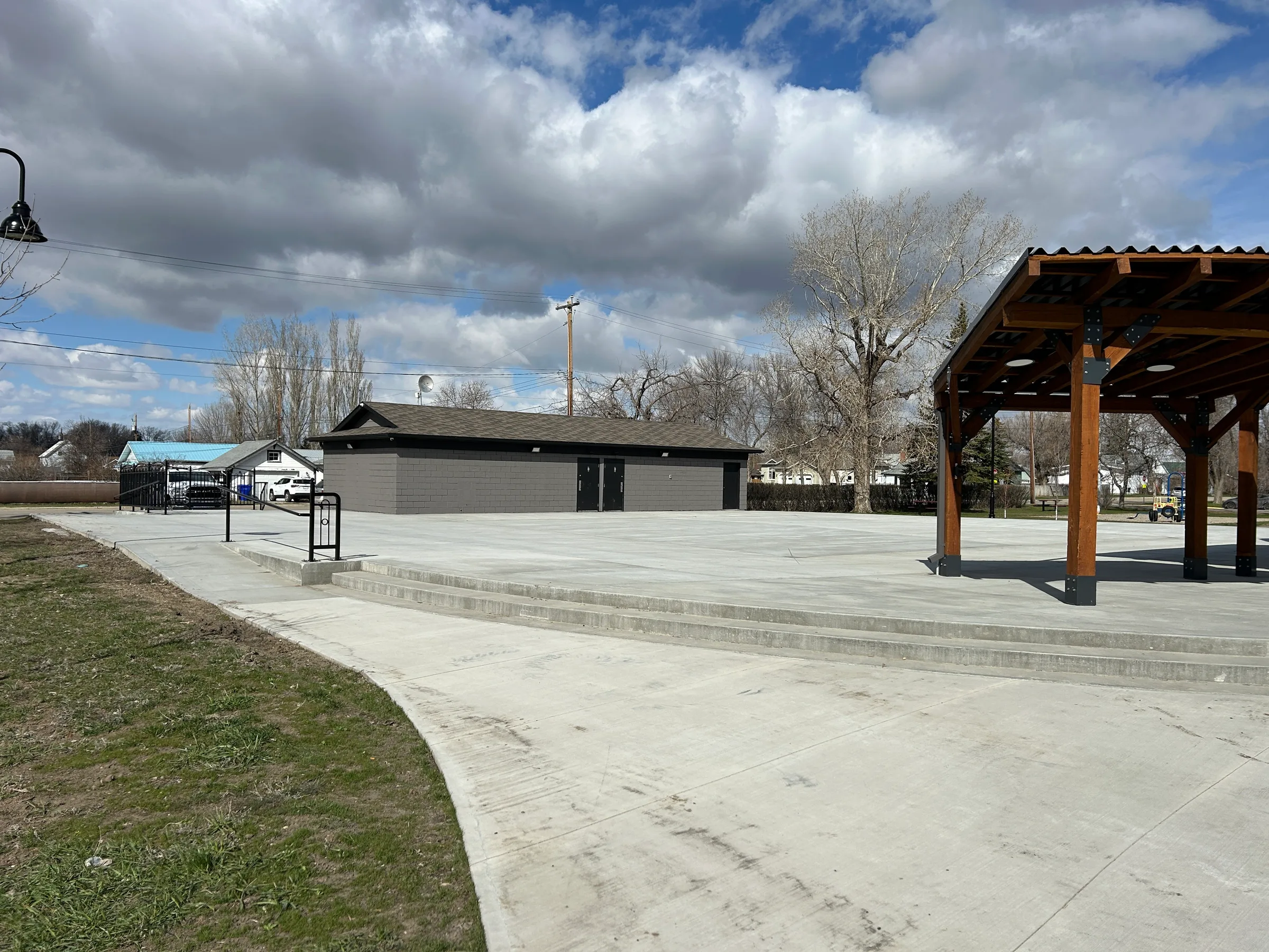 New concrete plaza and timber shade pergola beside a renovated park building at Amundsen Park Plaza, built by Premiere Builders