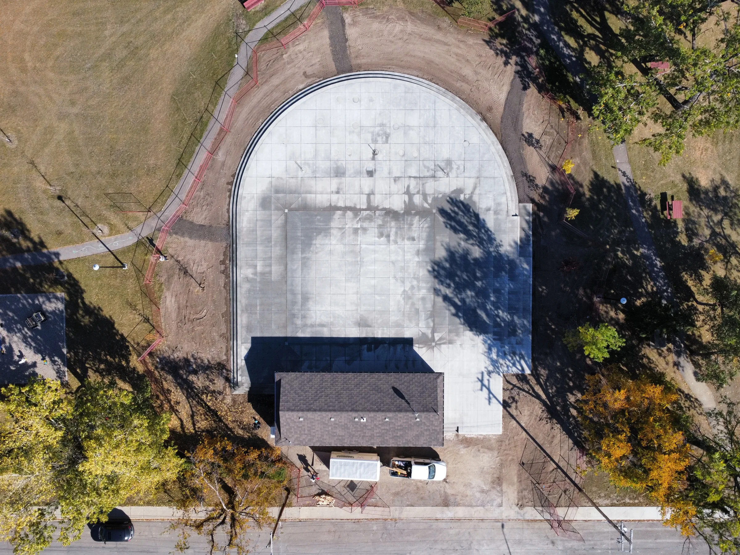 Overhead aerial view of the new rounded concrete plaza and park building surrounded by trees at Amundsen Park Plaza, built by Premiere Builders