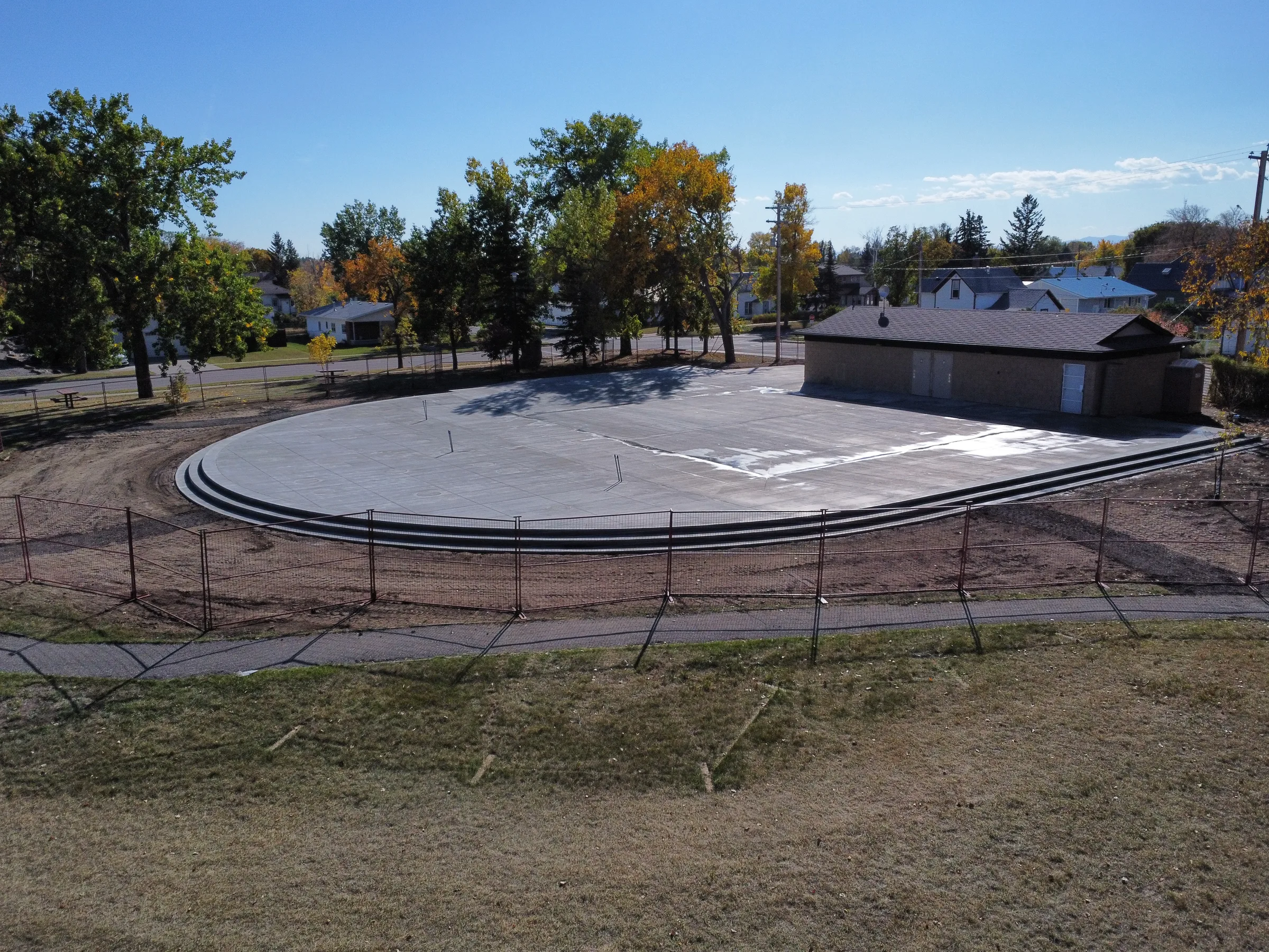 Low aerial view of the new oval concrete plaza with stepped edges in a residential park at Amundsen Park Plaza, built by Premiere Builders