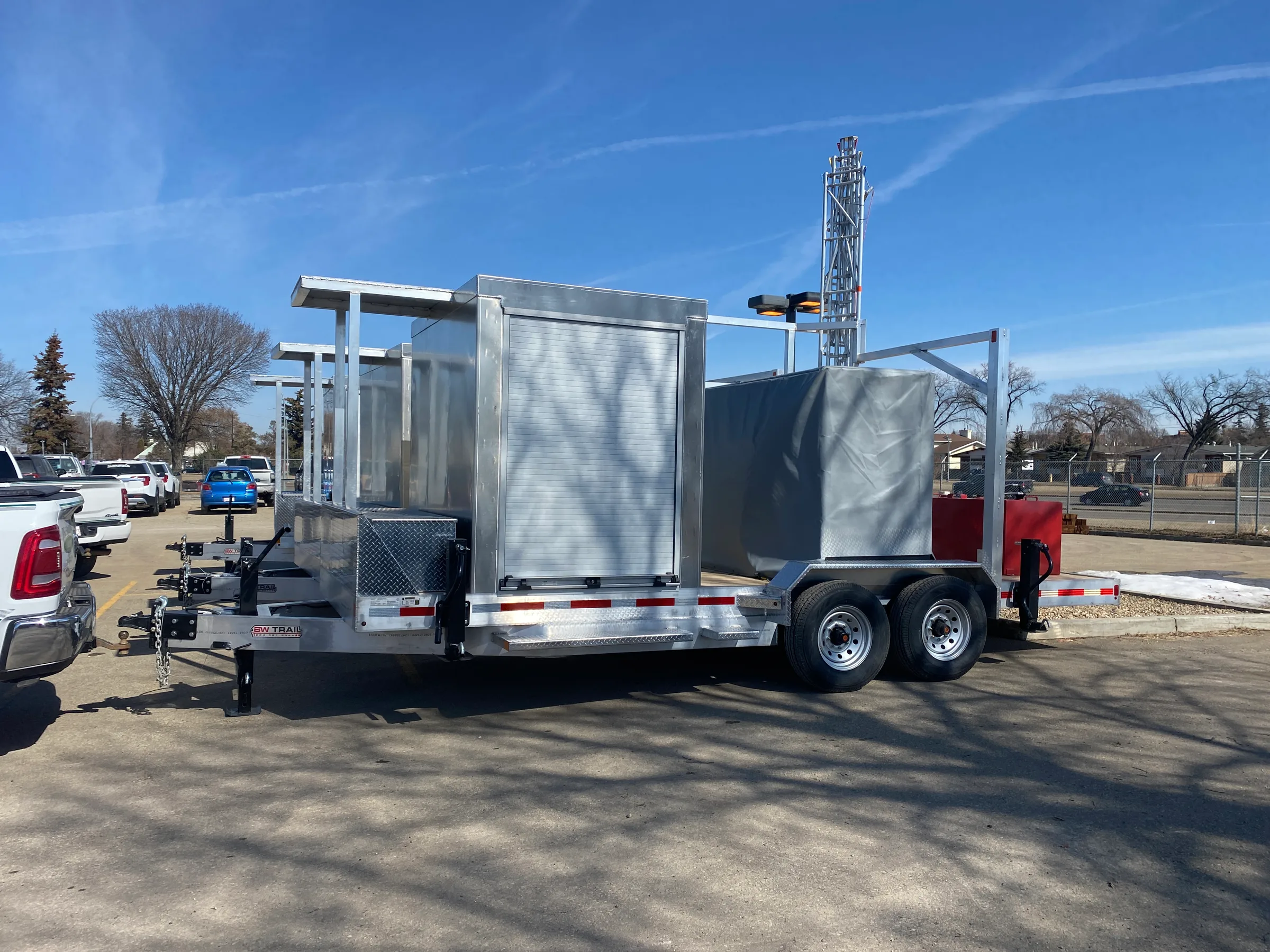 Pair of completed communication trailers with aluminum cabinets and fold down masts on a paved lot at Mobile Communication Trailers, built by Premiere Builders