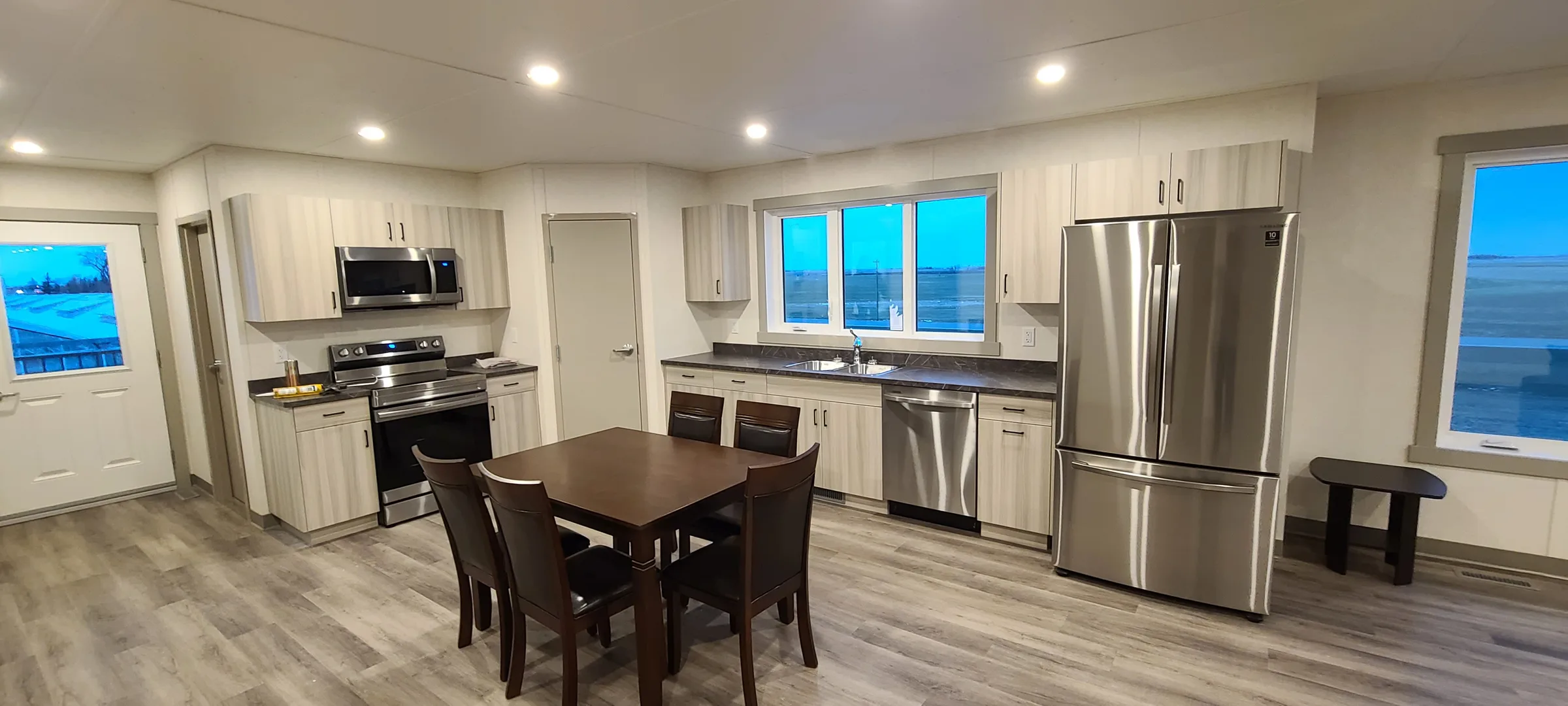 Bright kitchen with stainless appliances, light wood cabinets and a dining table at Employee Housing Complex, built by Premiere Builders