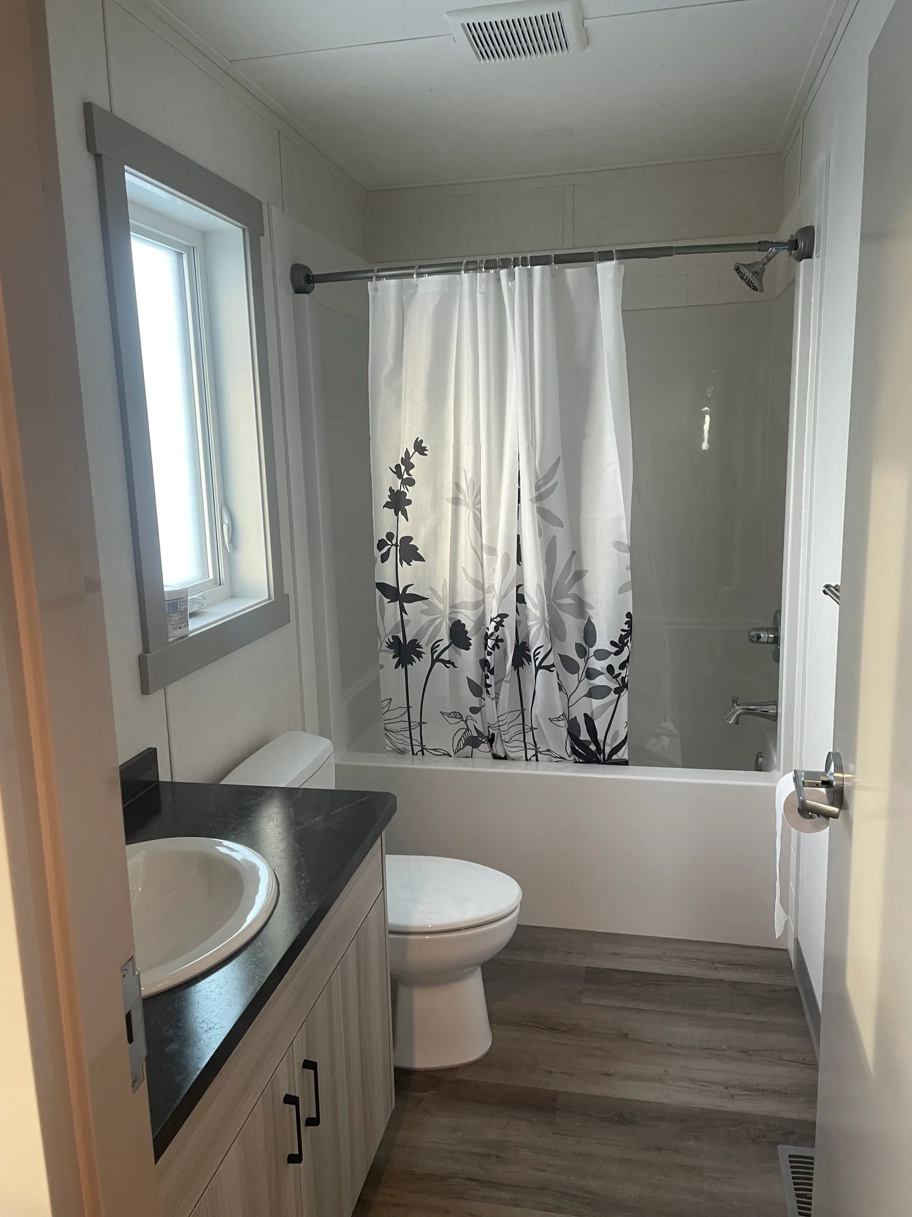 Finished bathroom with tub and shower, vanity with dark countertop and vinyl plank floor at Employee Housing Complex, built by Premiere Builders