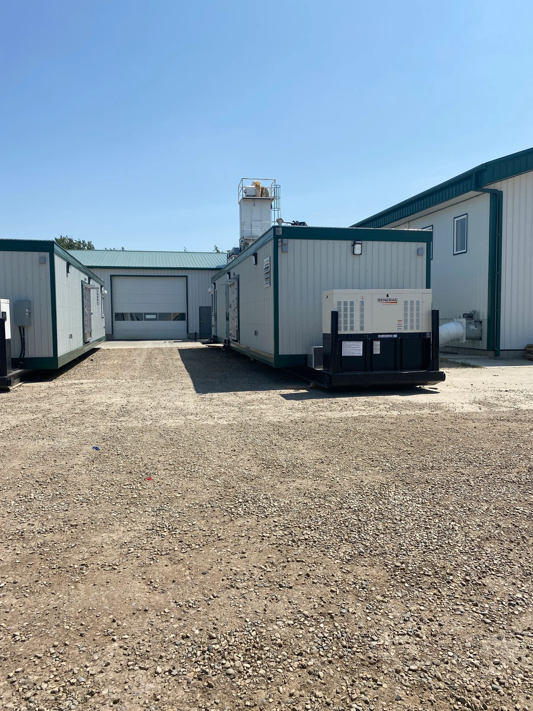 Completed modular units and generator set beside a steel shop building on a gravel site at Incident Supply Units, built by Premiere Builders