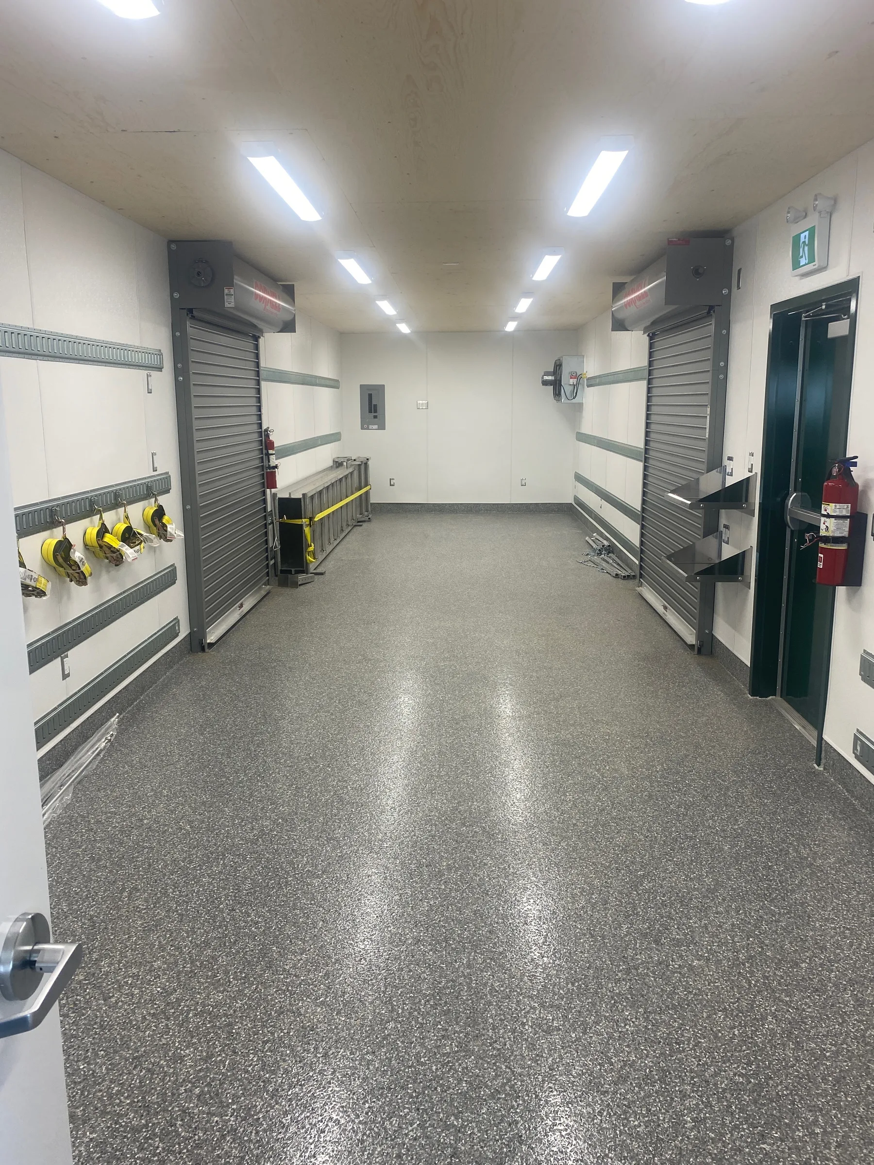 Bright modular unit interior with epoxy floor, roll up service doors, wall rails and LED lighting at Incident Supply Units, built by Premiere Builders