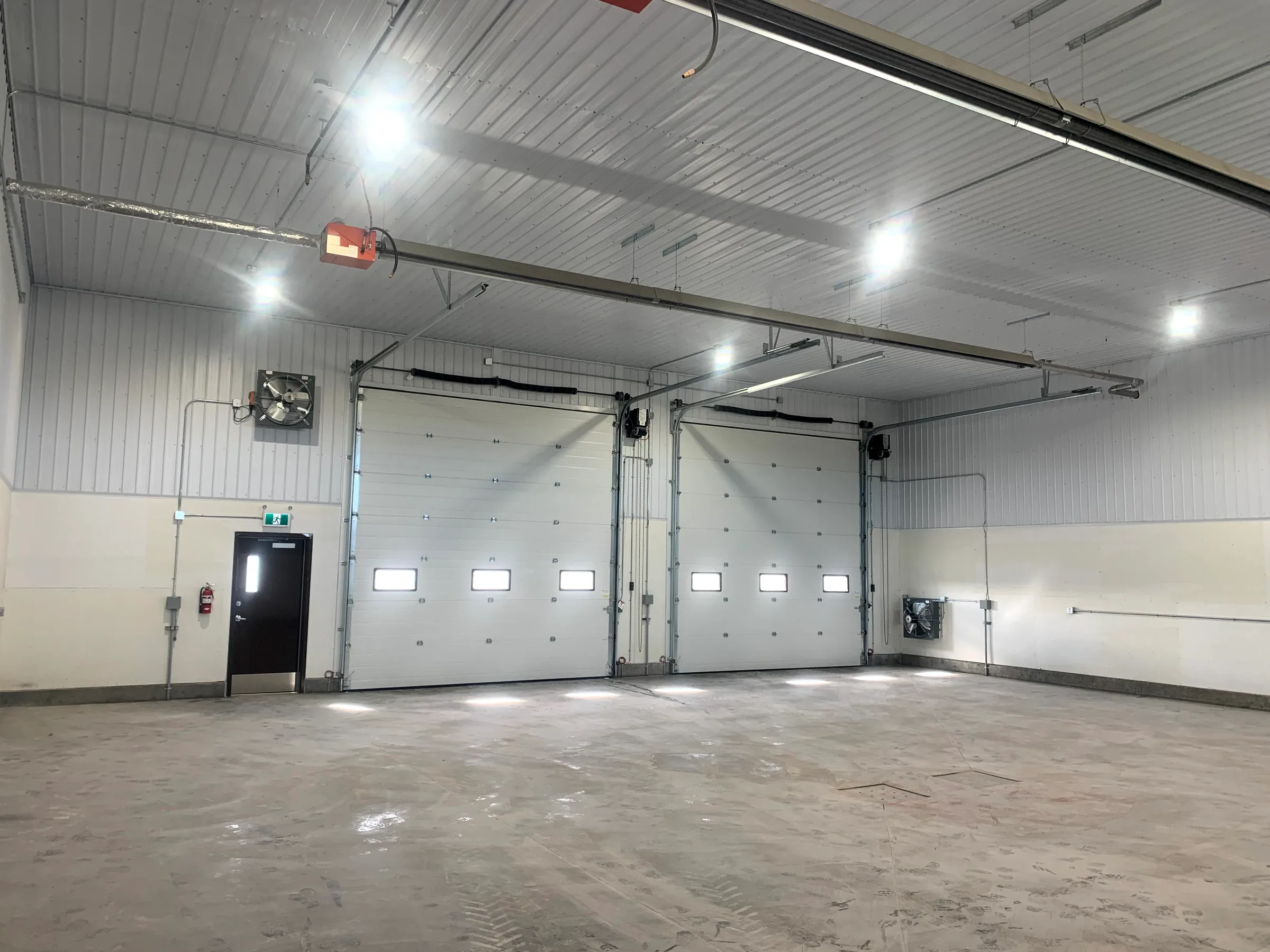 Bright shop interior with two insulated overhead doors, LED lights and unit heaters at City of Lethbridge Transportation Depot, built by Premiere Builders