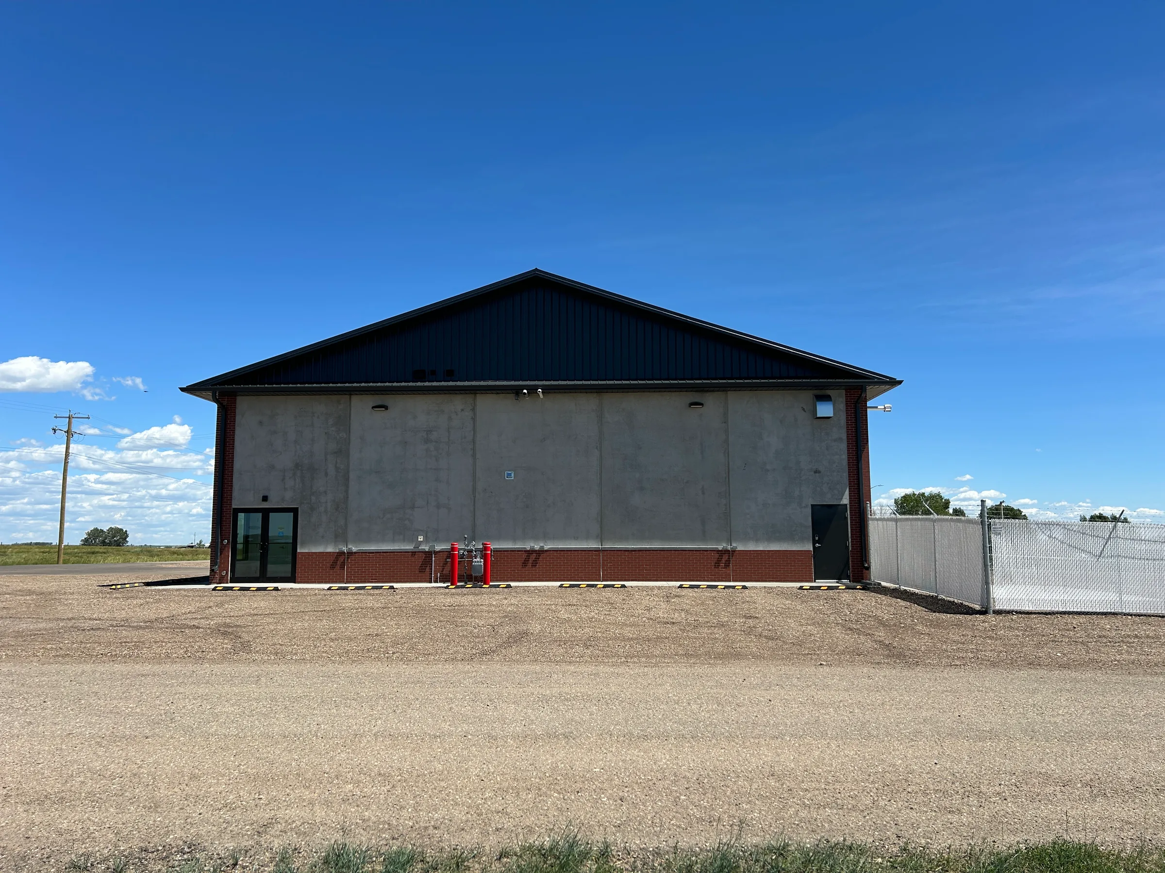 Gable end of the completed fire hall showing precast concrete walls and dark metal roof at Seven Persons Fire Hall, built by Premiere Builders