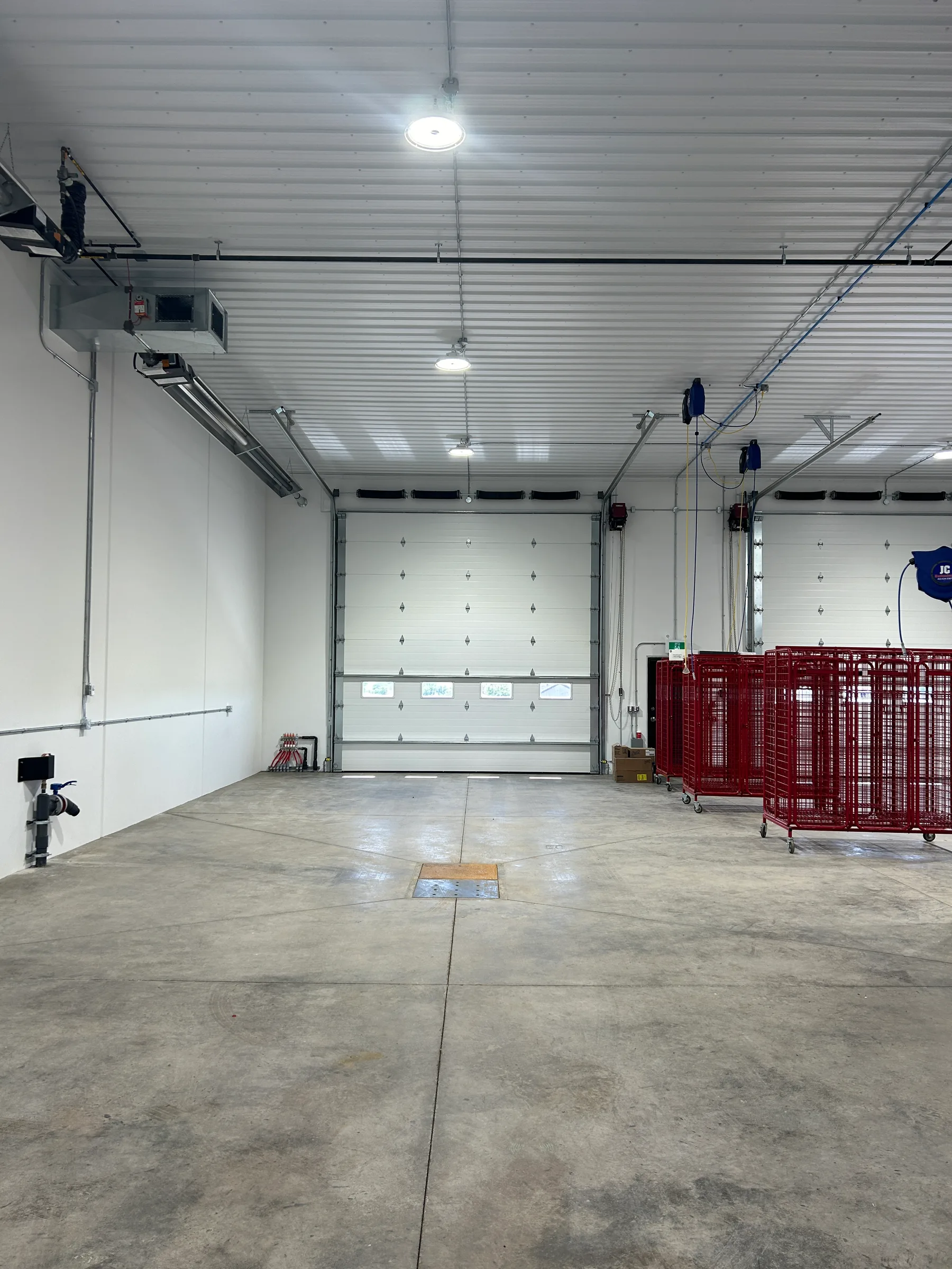 Bright apparatus bay interior with sealed concrete floor, overhead doors and gear racks at Seven Persons Fire Hall, built by Premiere Builders
