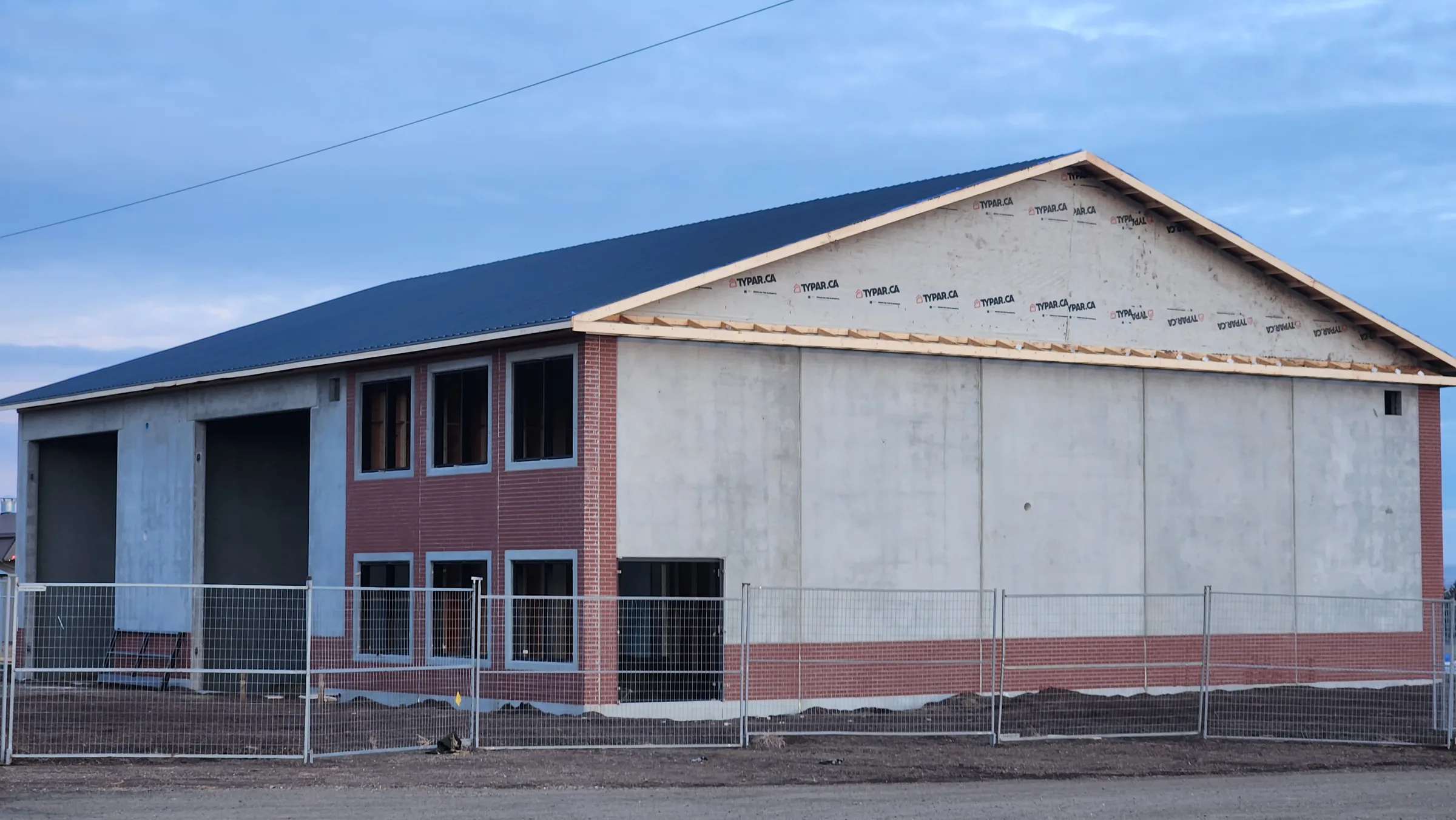 Fire hall nearing completion with precast walls, brick-faced office wing and new metal roof at Seven Persons Fire Hall, built by Premiere Builders